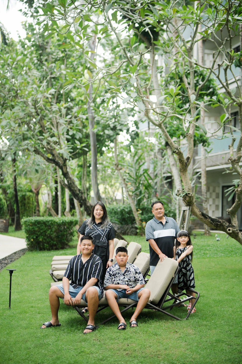 family photography at Movenpick Jimbaran Bali with parents and children sitting together on a green garden lawn