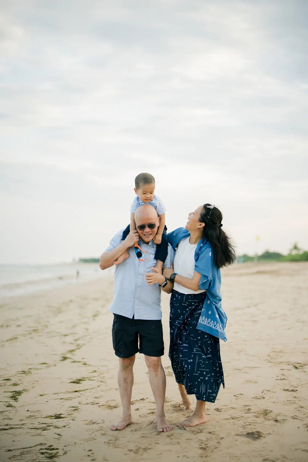 Parents embracing their son during a relaxed family photography session at Nusa Dua Beach Bali