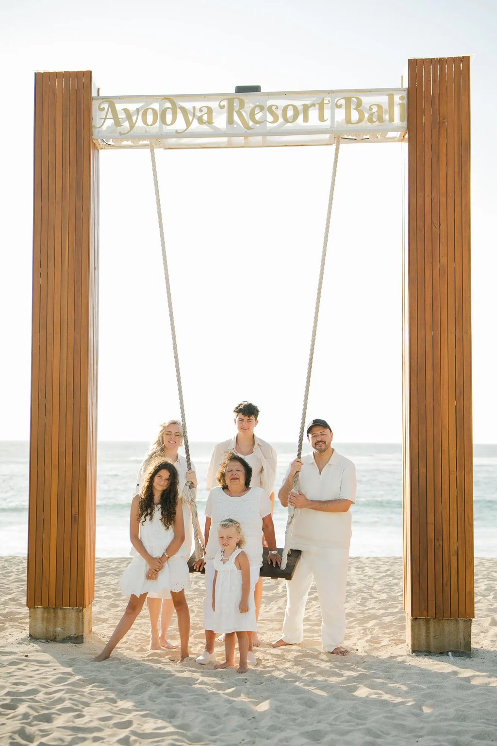 Parents embracing on the iconic beach swing at Ayodya Resort Bali in Nusa Dua