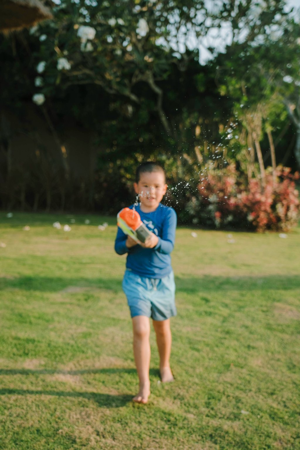 Children playing with water guns during a family photography session at AYANA Villas Jimbaran Bali