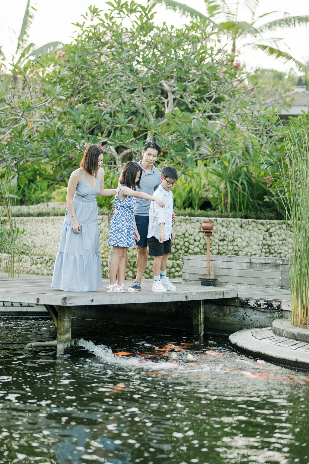 Family enjoying time together in a tropical garden during a luxury family photography session at The Ritz-Carlton Bali.