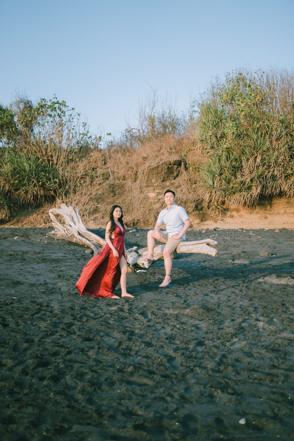 Wide beach portrait of intimate couple near rock formation at Pantai Nyanyi Bali.