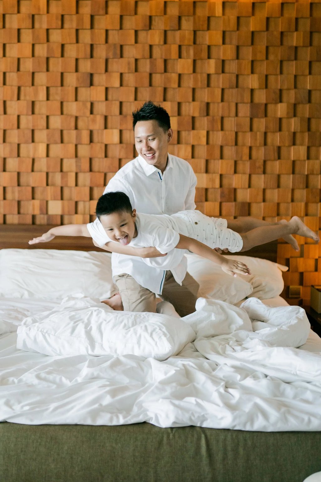 Playful family moment on the bed during a relaxed indoor family photography session at Anantara Uluwatu.