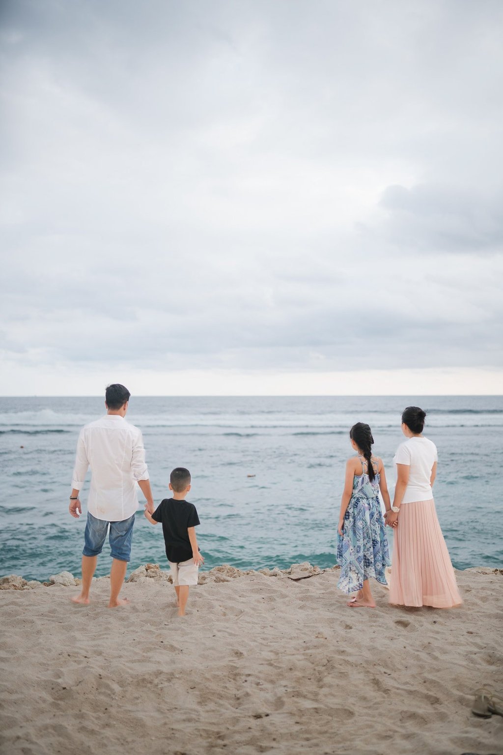 Family standing together along the cliffside coastline of Melasti Beach Bali during a relaxed family photography session