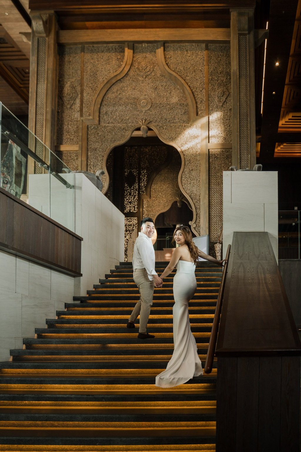 Couple walking down the grand staircase during a luxury prewedding photoshoot at Apurva Kempinski Bali