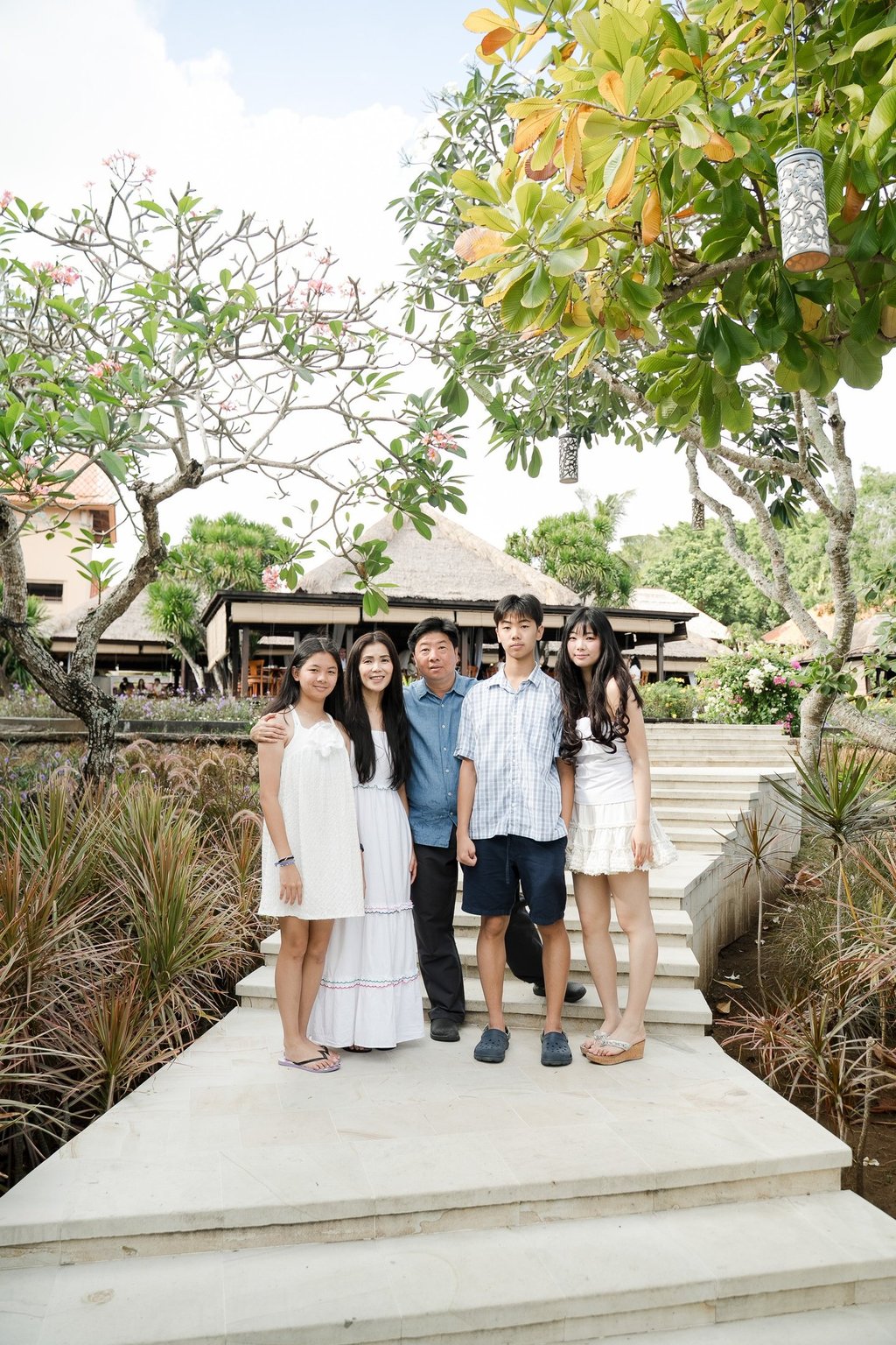 Family gathered in a tropical garden setting during a natural lifestyle session at Ayana Resort Jimbaran Bali