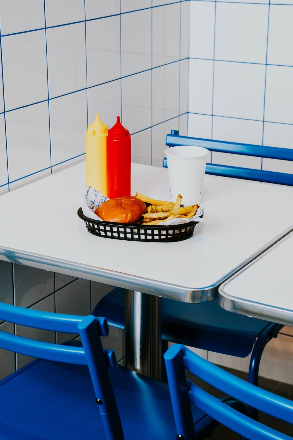 Burger amb patates i salses servides en una taula de Flipa amb estètica minimalista blava i blanca