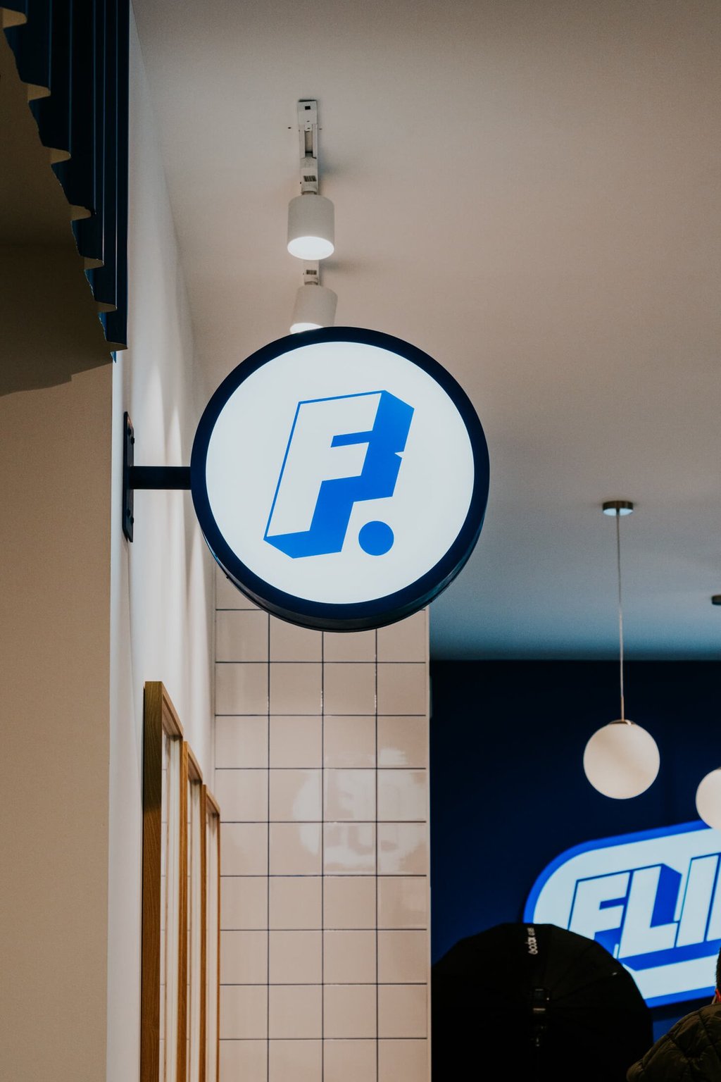 Cartel redondo con la F de Flipa iluminado en el interior del restaurante