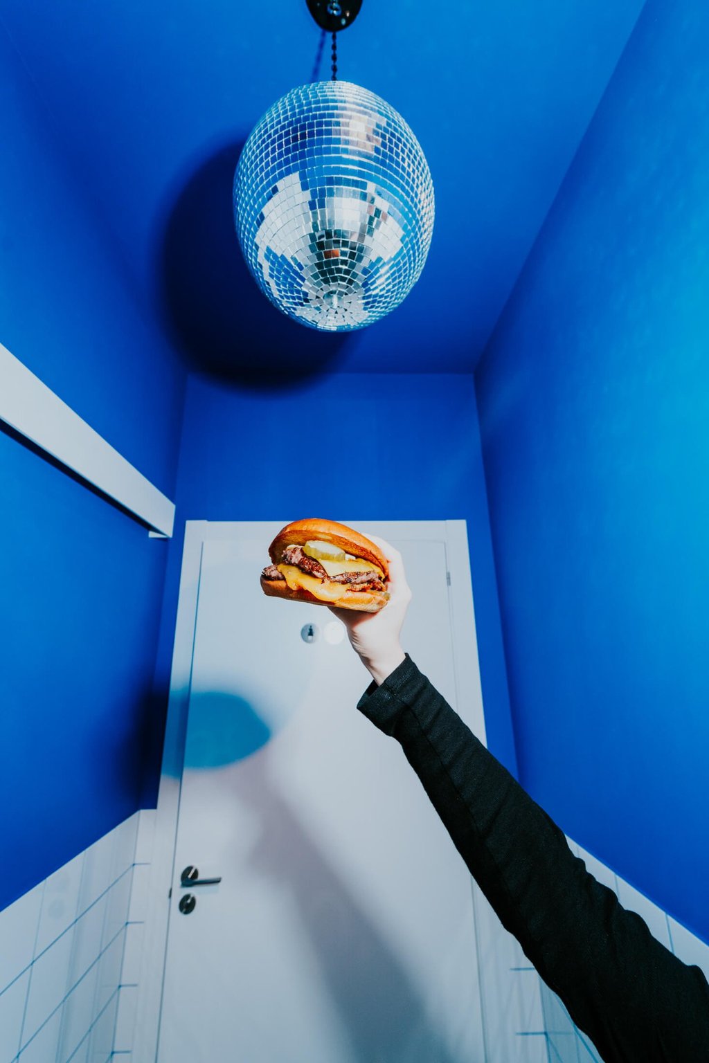 Burger de Flipa sostinguda sota una bola de discoteca en un espai blau, estil original i atrevit