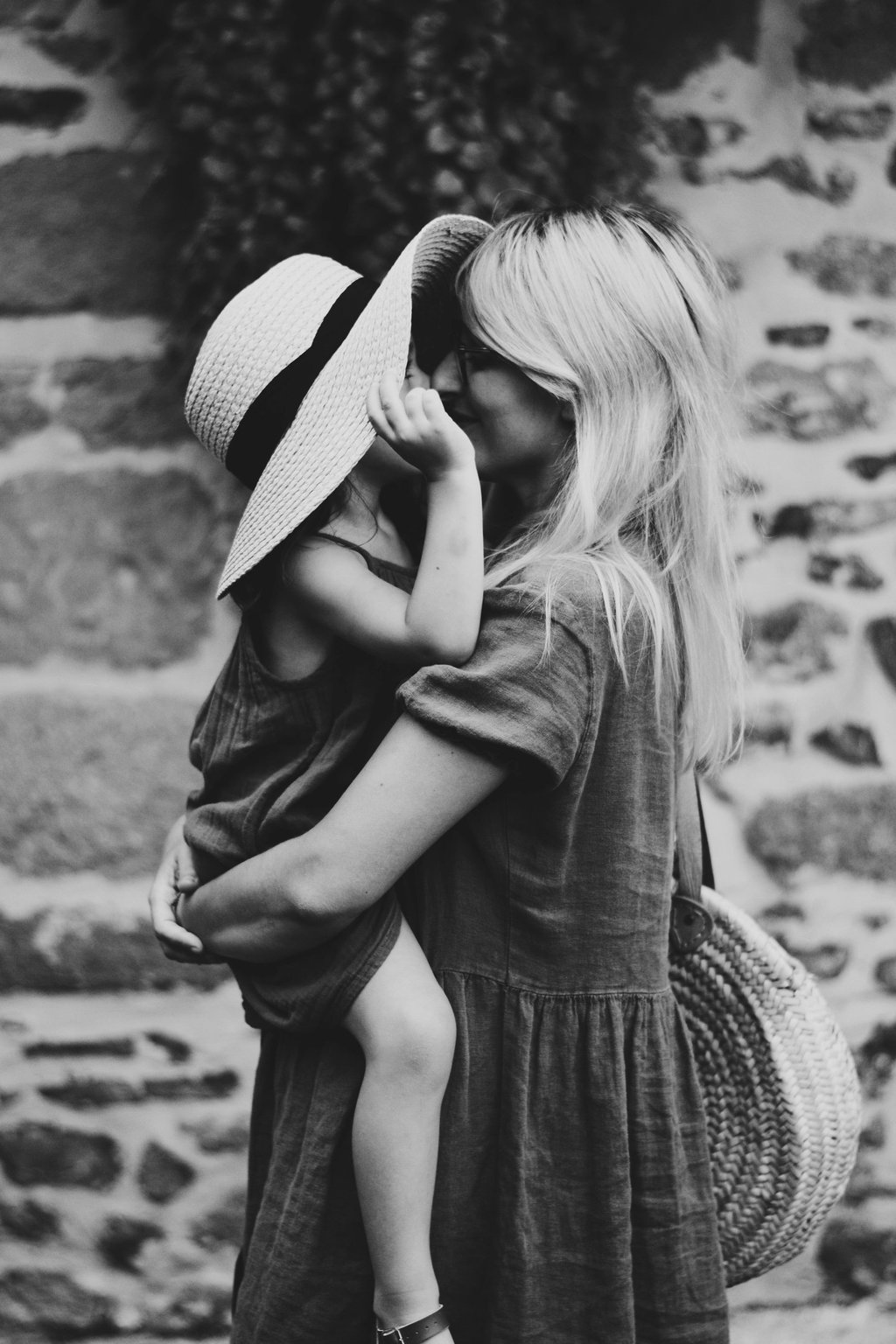 a woman in a hat and sunglasses is holding a baby
