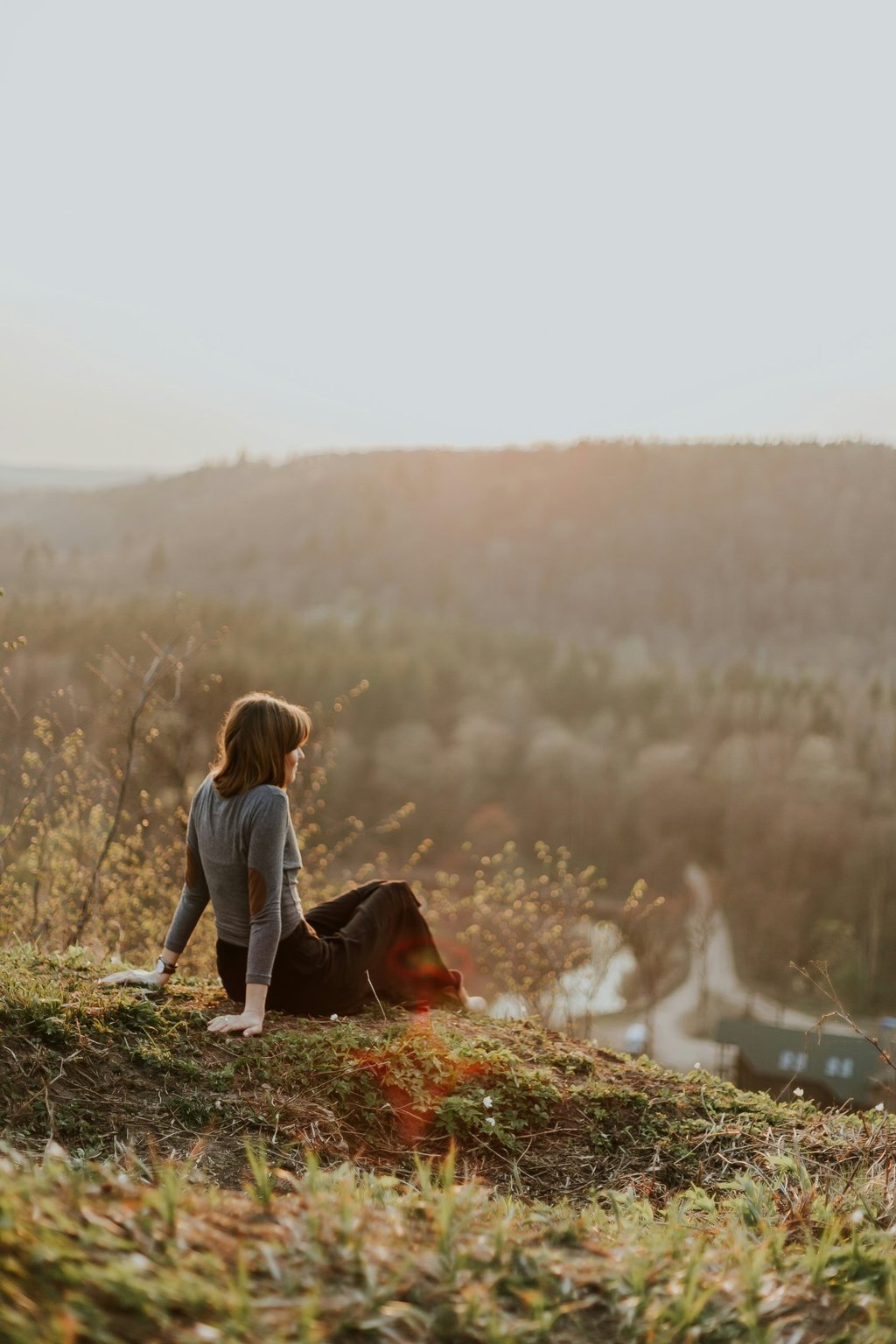 a woman sitting on a hill with a dog