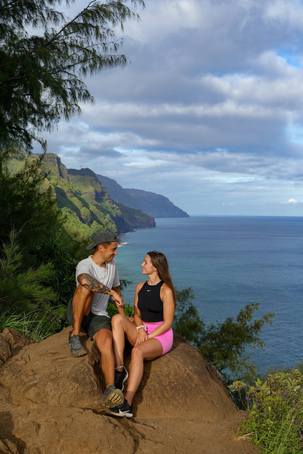 a man and woman sitting on a rock in hawaii