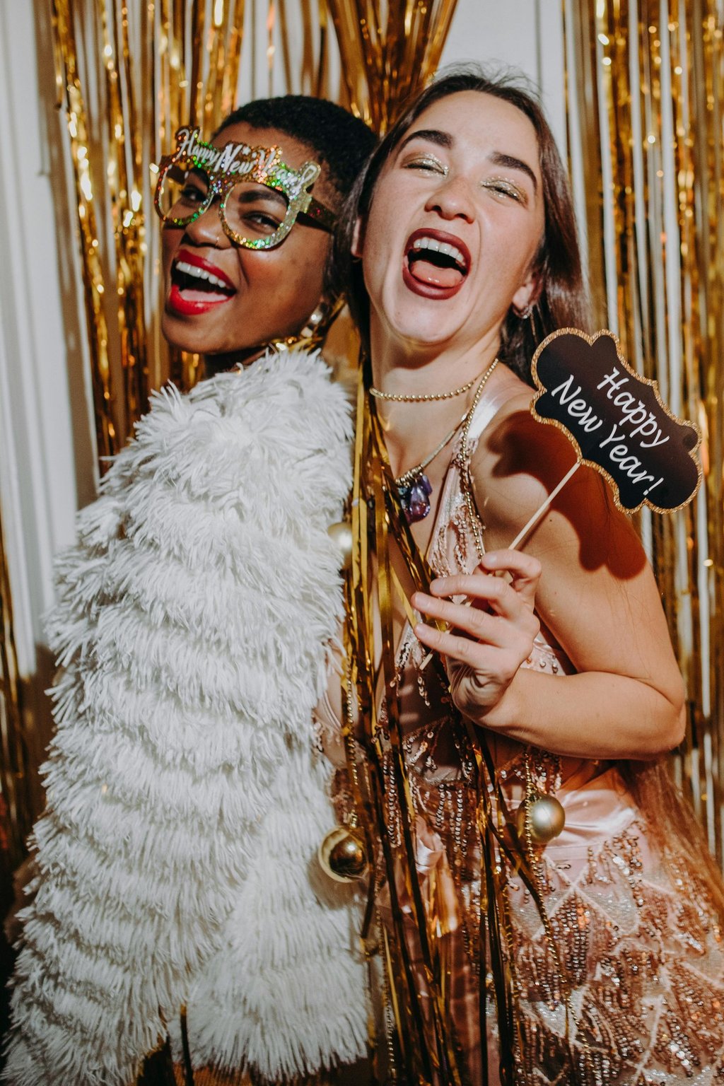 femmes souriantes portant des accessoires festifs dans une cabine photobooth, célébrant le Nouvel An