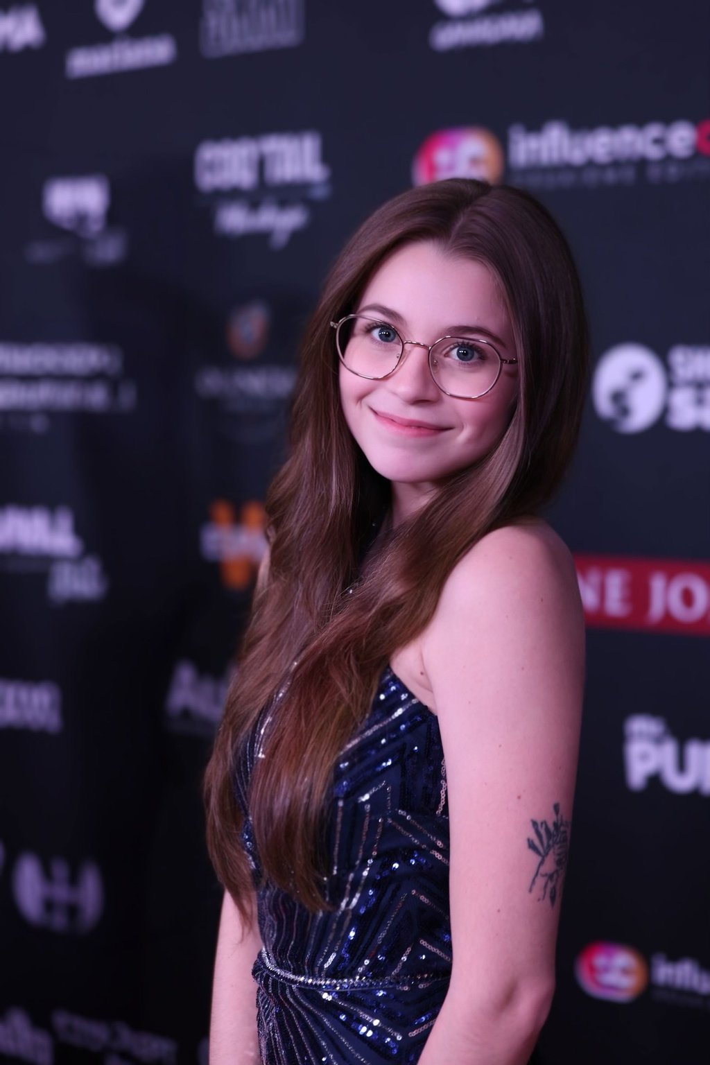 a woman with glasses and a tattoo on her arm