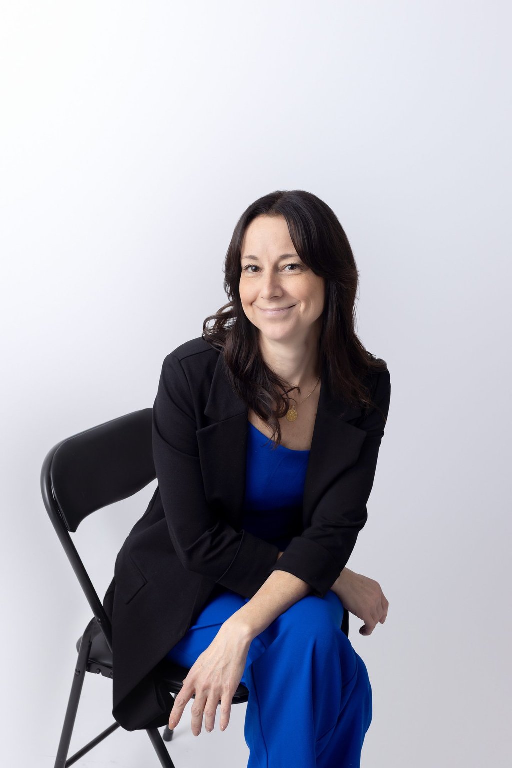 a woman wearing a blue outfit and black jacket sitting down