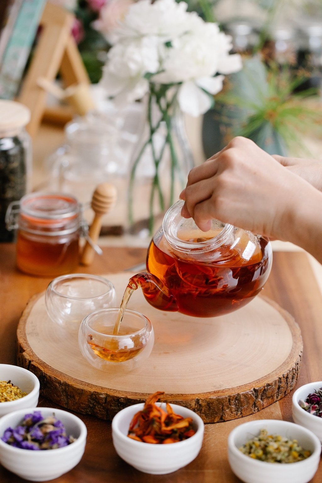 Woman brewing herb tea and white flowers on the table