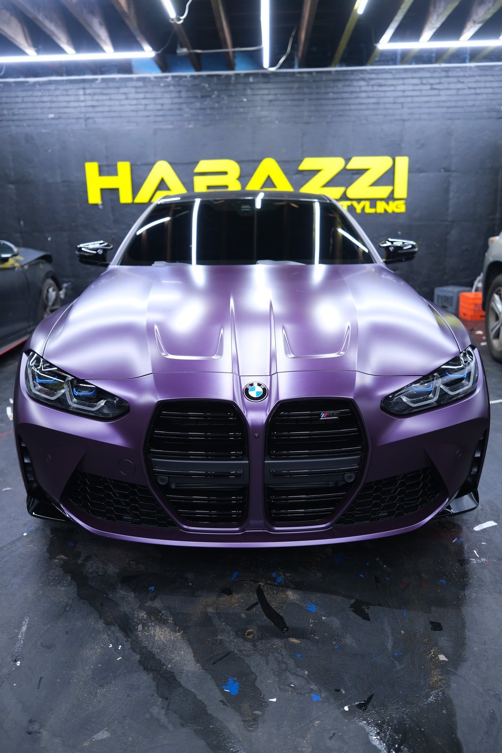 Front view of a BMW M4 with a matte metallic ppf car wrap at a professional auto styling shop.