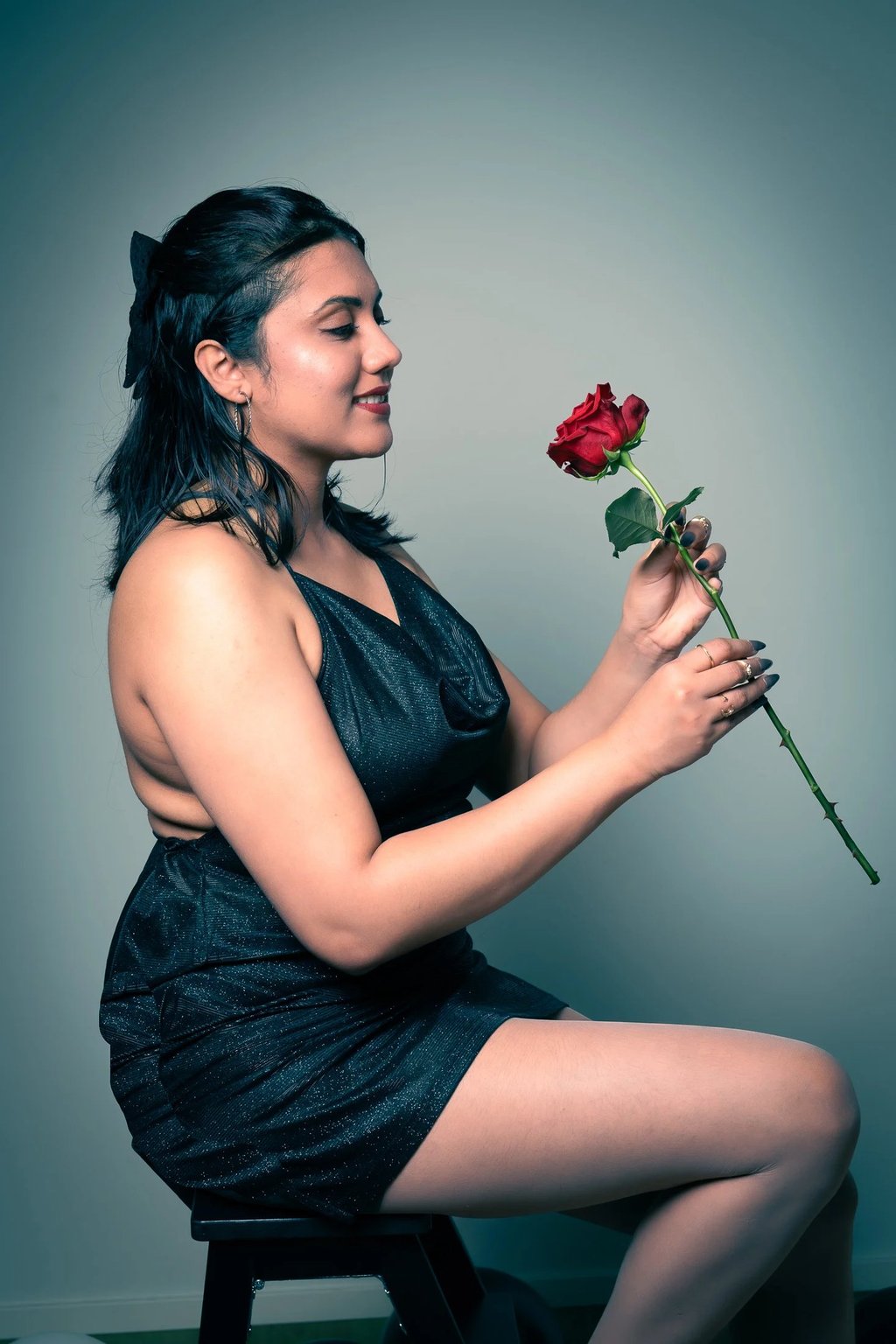 a woman in a black dress sitting on a stool