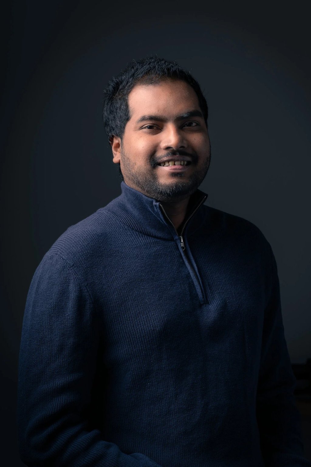 a man in a blue sweater in a dark background