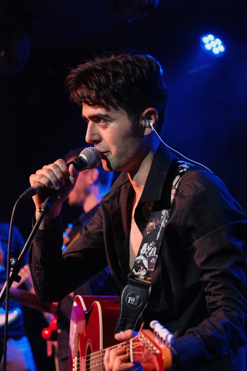 Live Brighton performance by rock and roll singer Olly Williams with his band, playing guitar on stage.