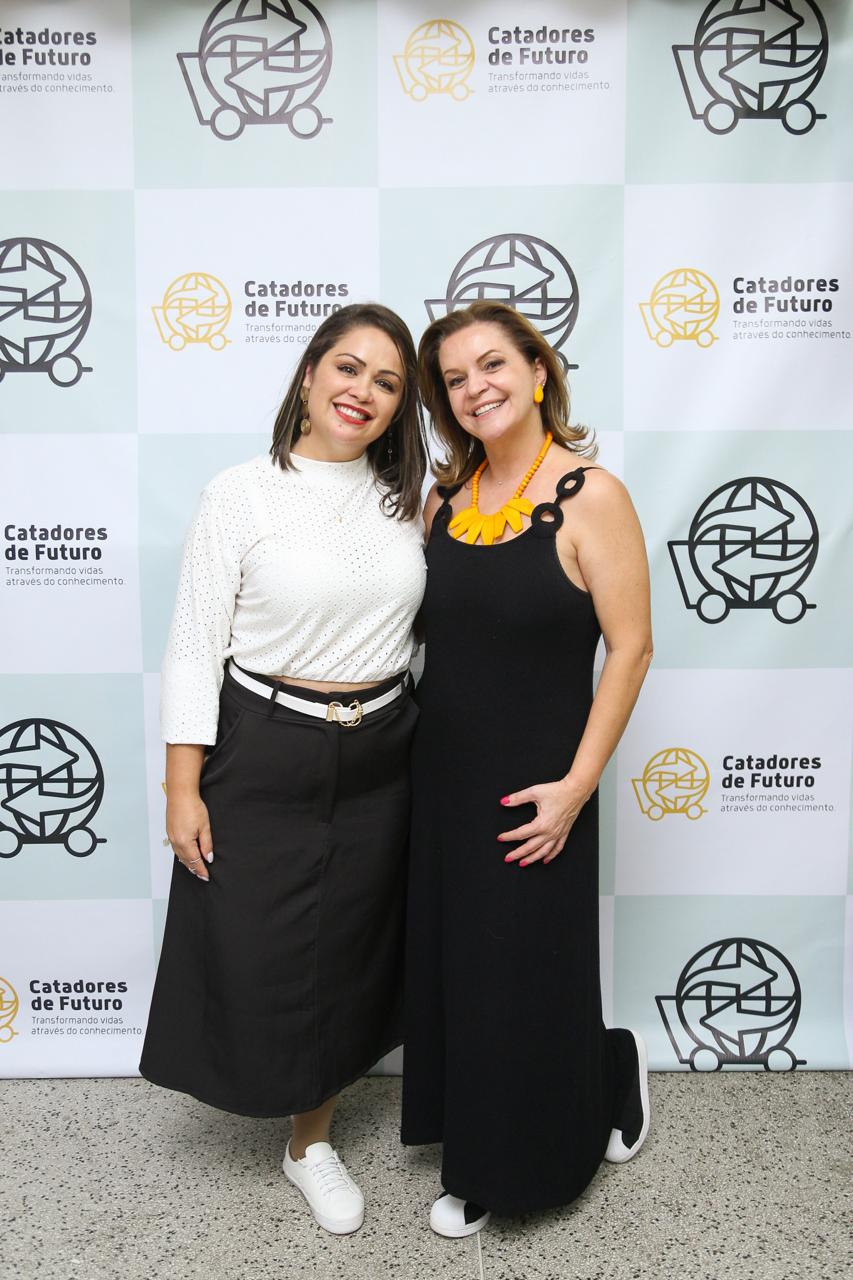 two women standing next to each other in front of a wall with a sign that