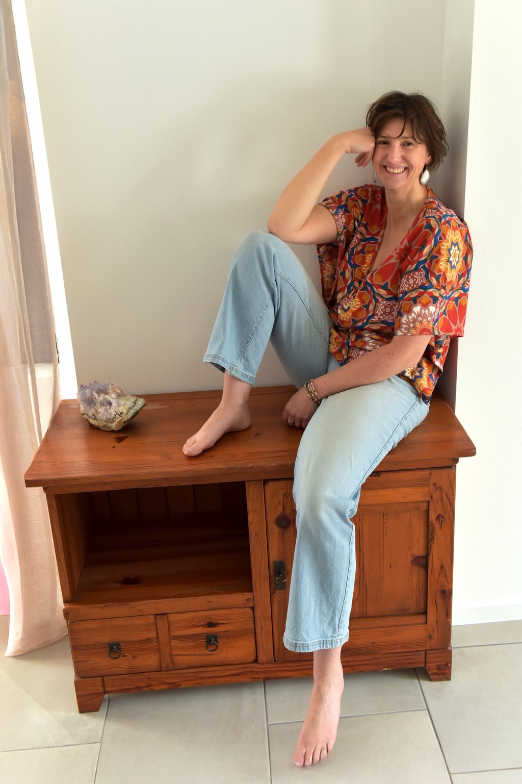 julie mansencaut sitting on a wooden bench with a bookcase