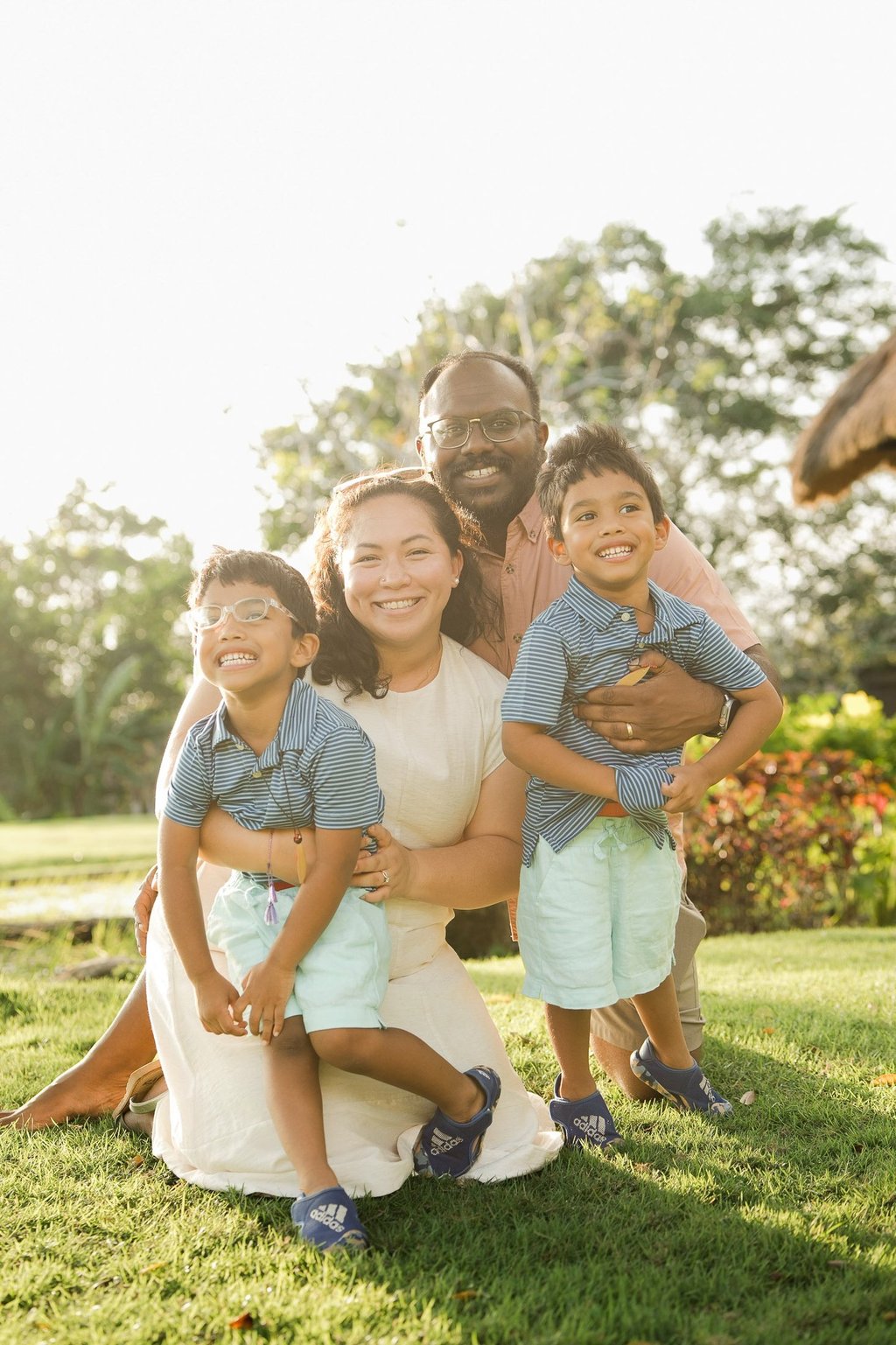 mother kneeling and embracing her children on the lawn at rimba by ayana bali during natural bali family photography