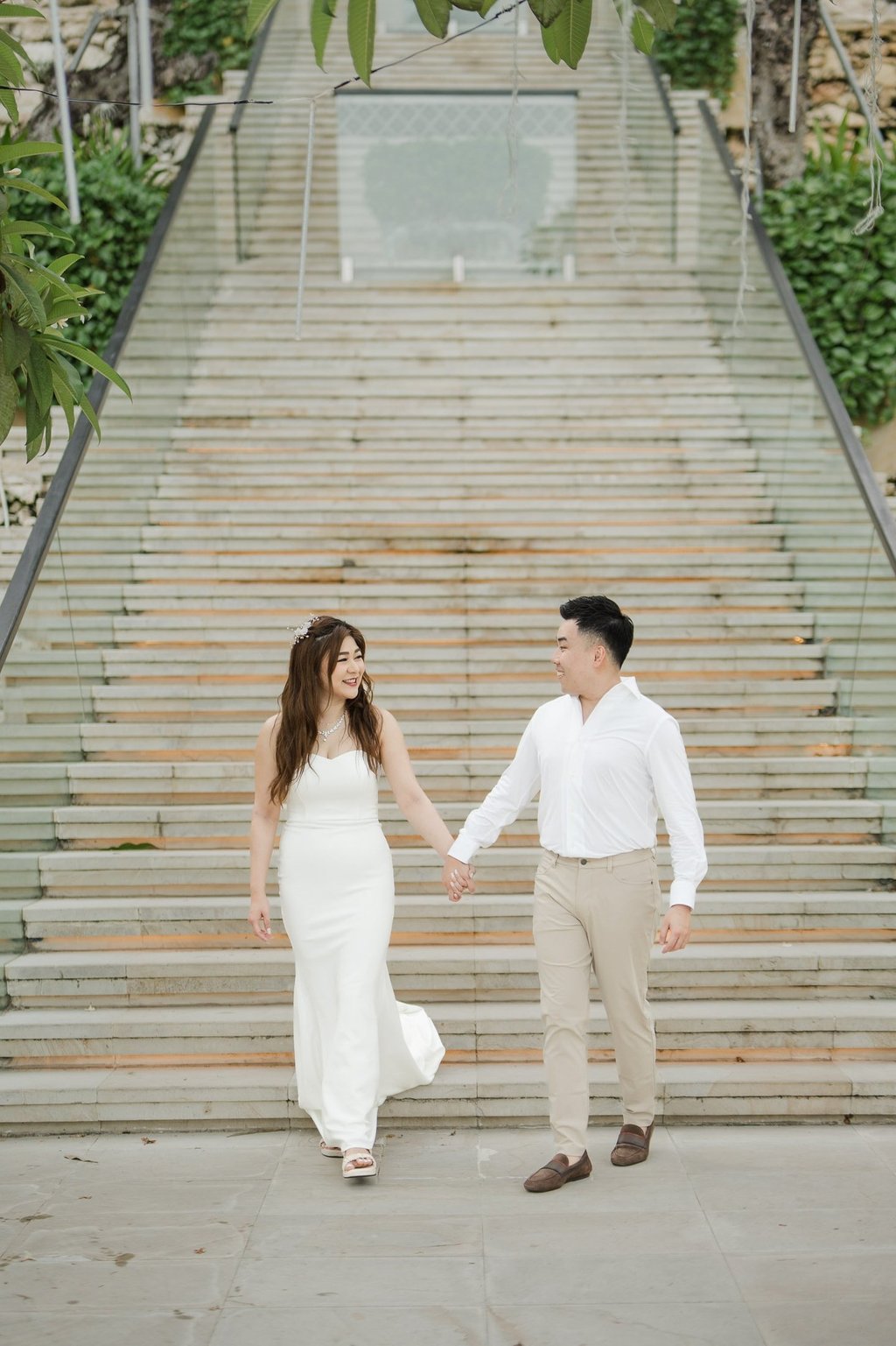 Couple walking down the iconic grand staircase during a prewedding photoshoot at Apurva Kempinski Bali