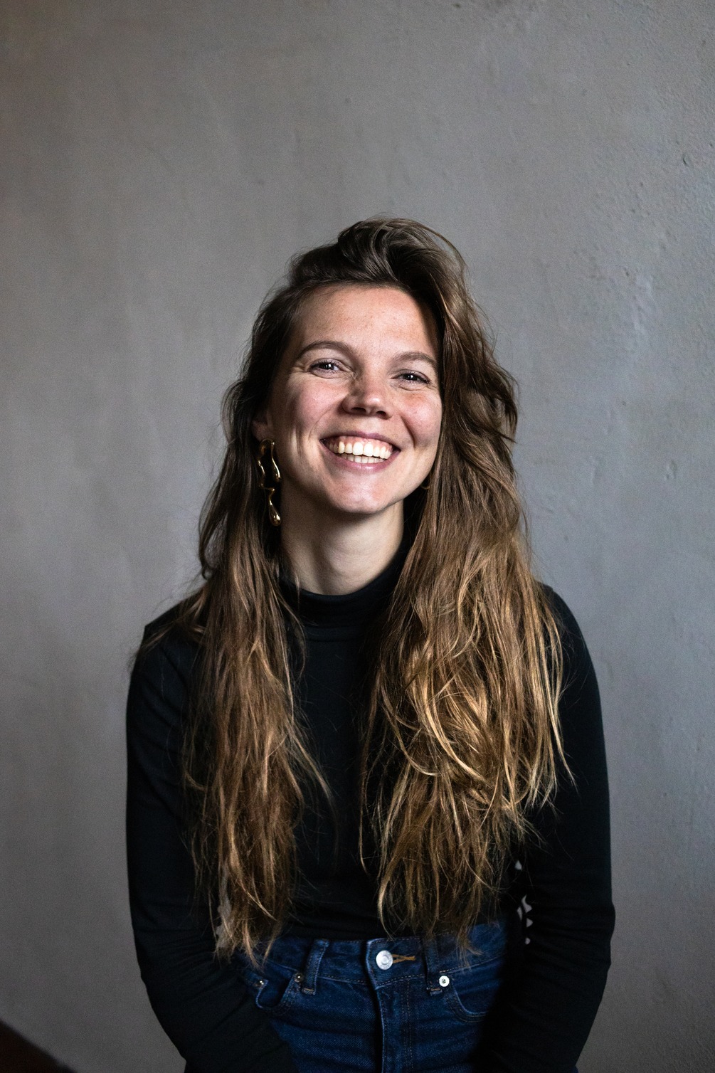 Young, female public speaking trainer, smiling in the camera confidently and happy