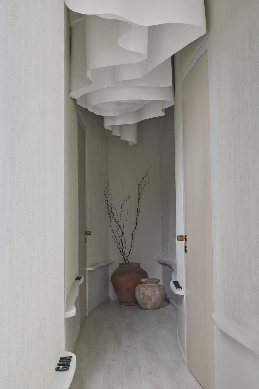Modern minimalist hallway design with curved walls and artistic ceiling installation