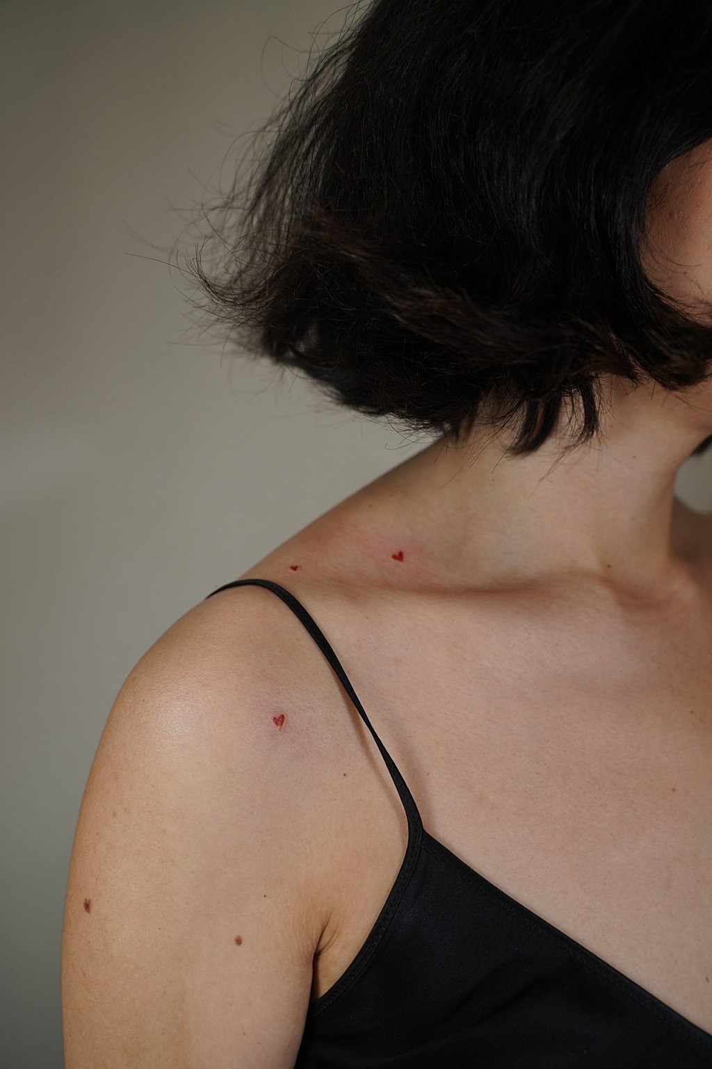 Tatuaje fineline en Madrid de corazón micro en tinta roja en el escote cerca del hombro