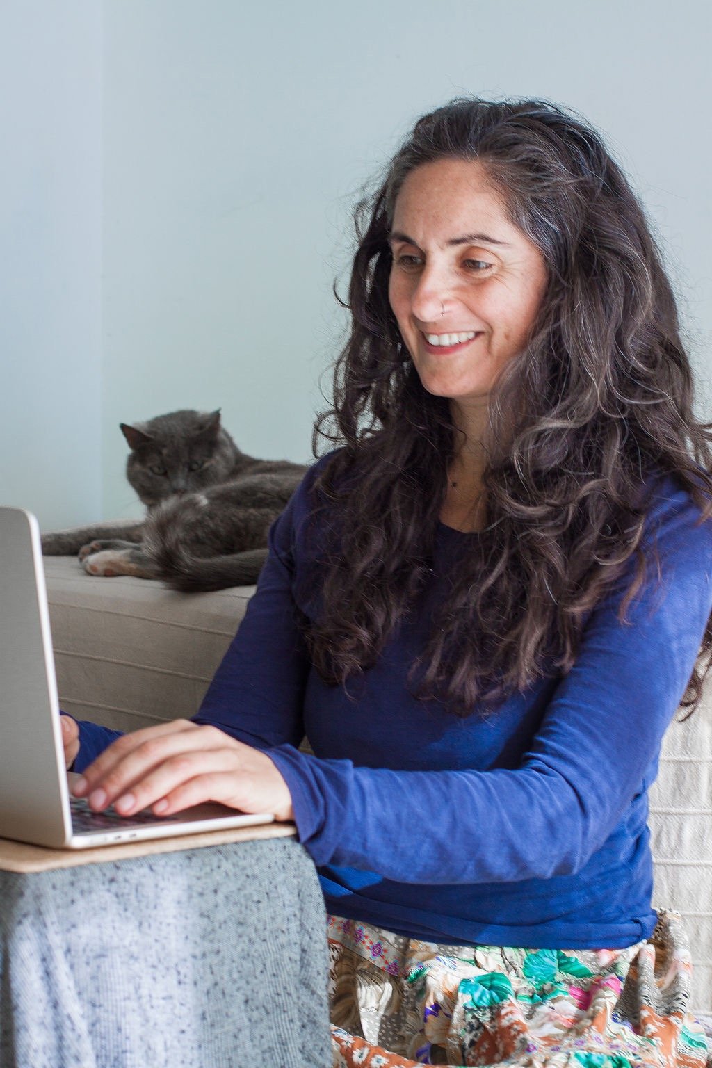Porträt von Juliette Maggu am Laptop mit einer Katze im Hintergrund