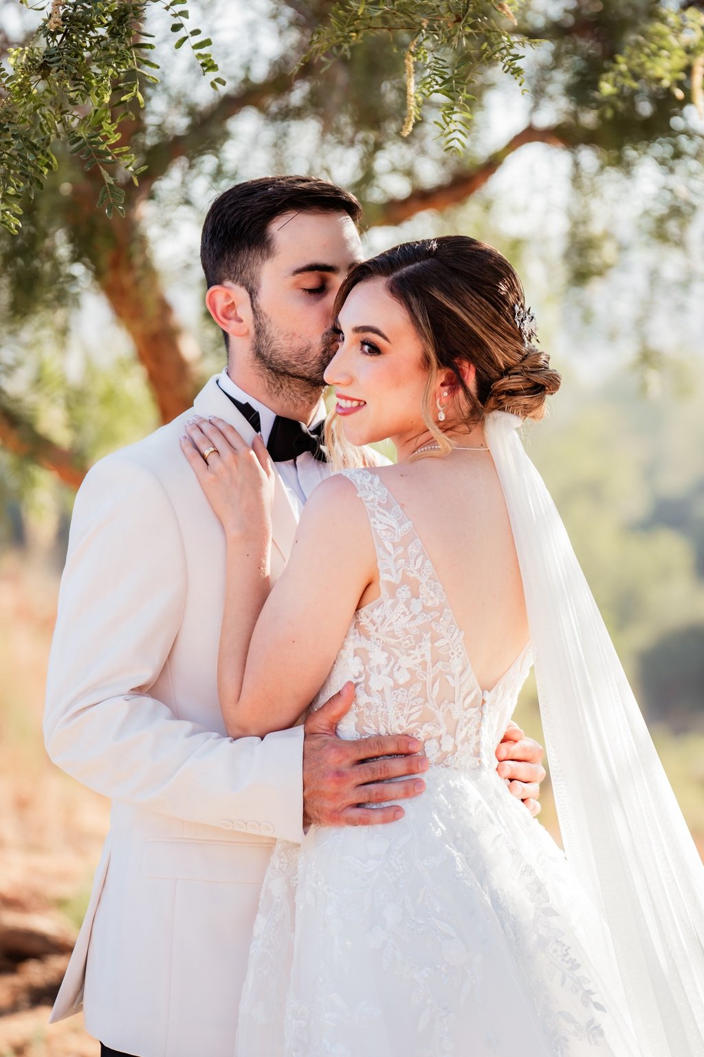 a bride and groom standing in front of a tree