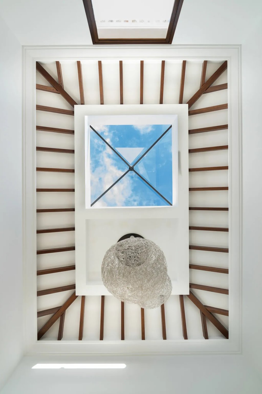 Atrium skylight with exposed wooden beams and contemporary chandelier