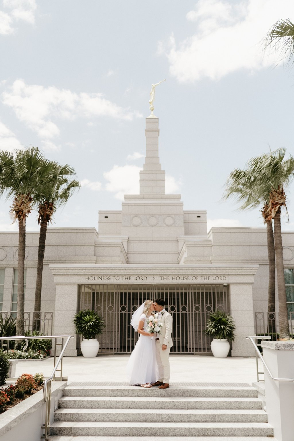 a bride and groom standing in front of a temple