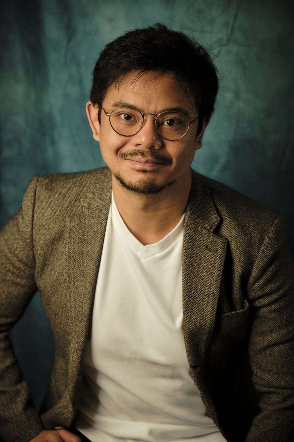 a man in a suit and glasses poses for a portrait