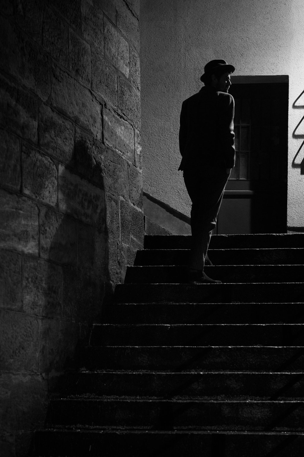 a man in a hat and a suit jacket is walking up stairs