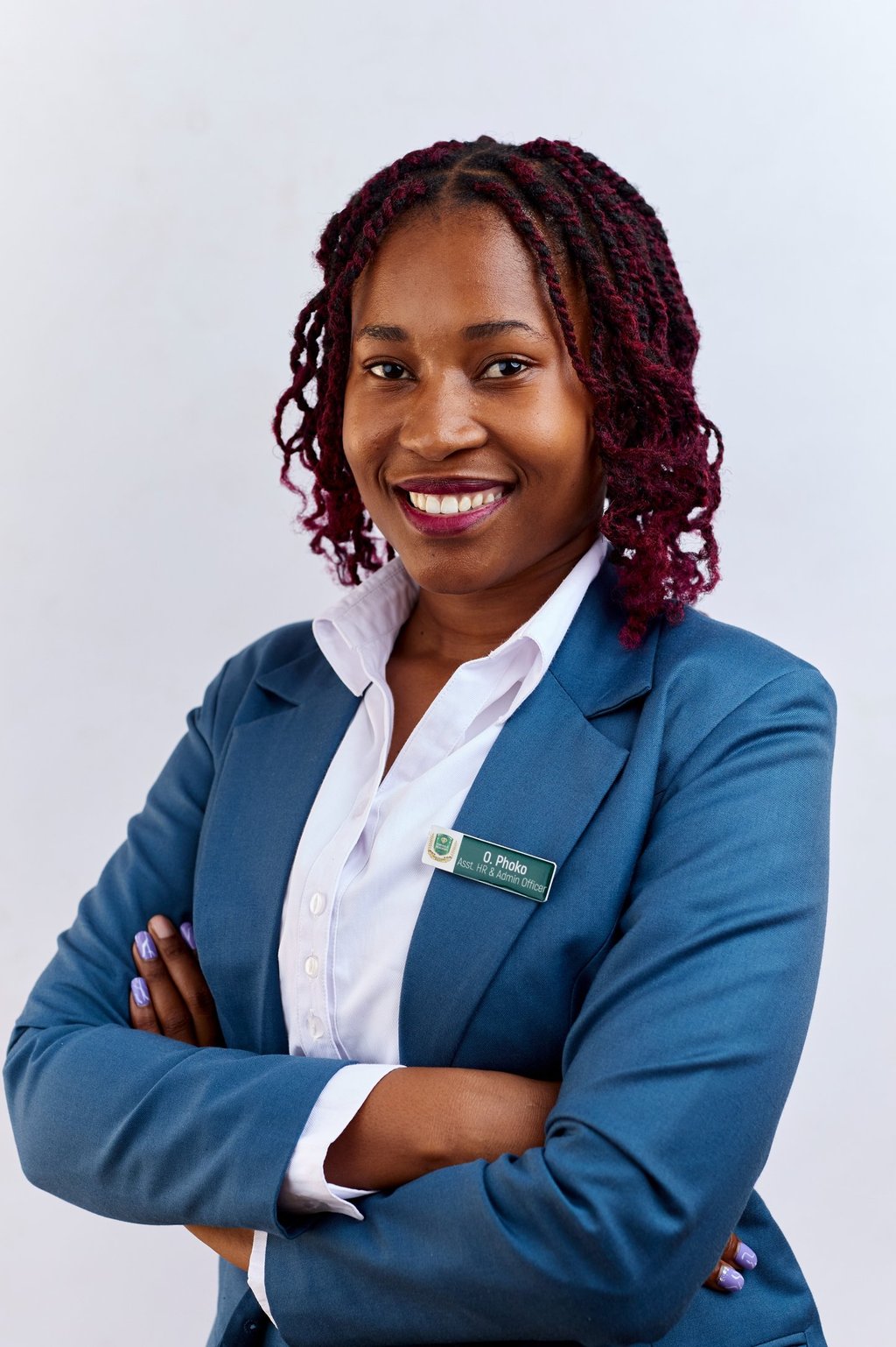 Smiling female professional with red locs wearing a blue business suit and name tag.