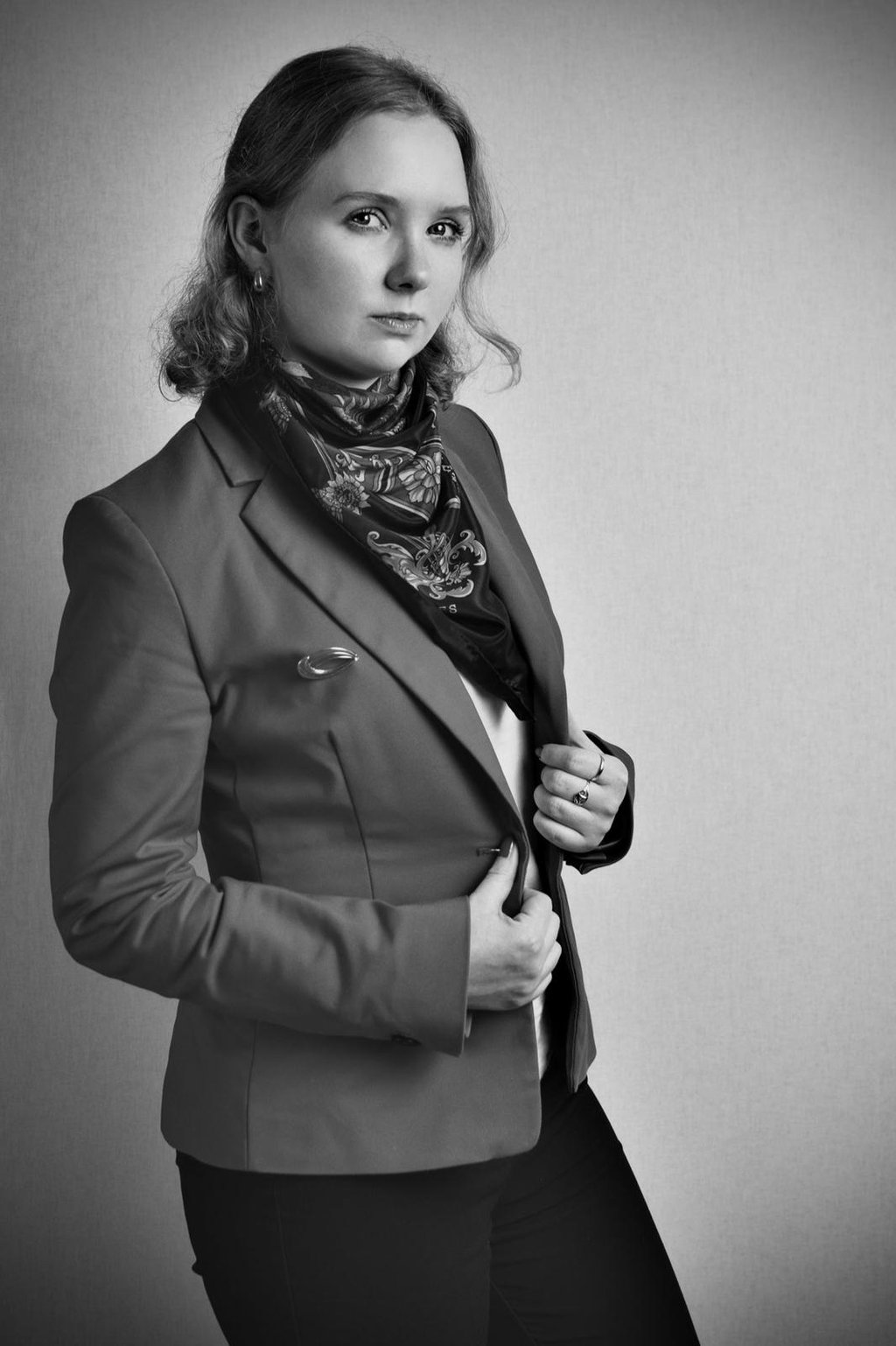 a woman in a suit and scarf with a scarf around her neck