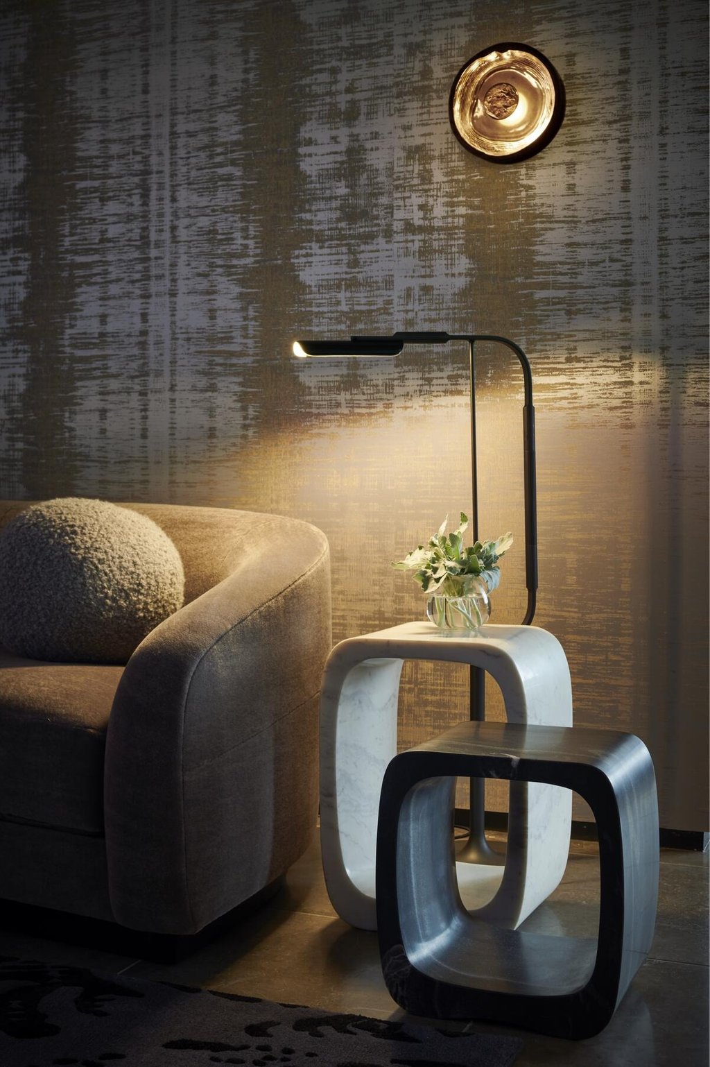 Modern living room with a sleek floor lamp, marble side table, and elegant textured gold wallpaper.