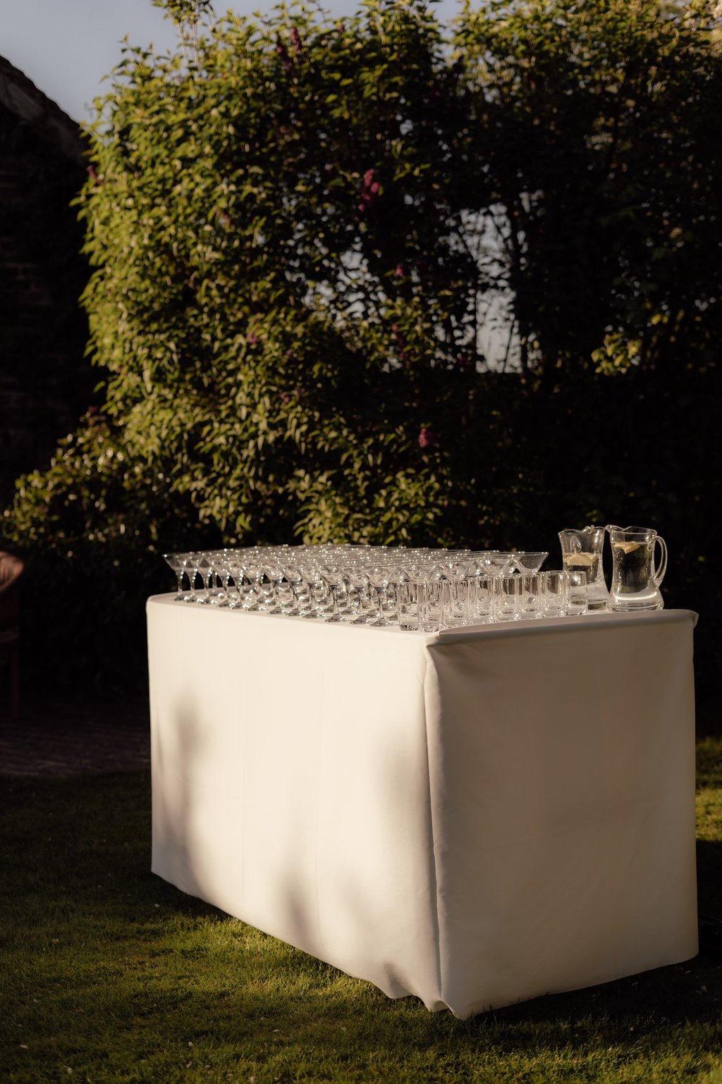 table in the garden full of glasses and jugs of water with lemon