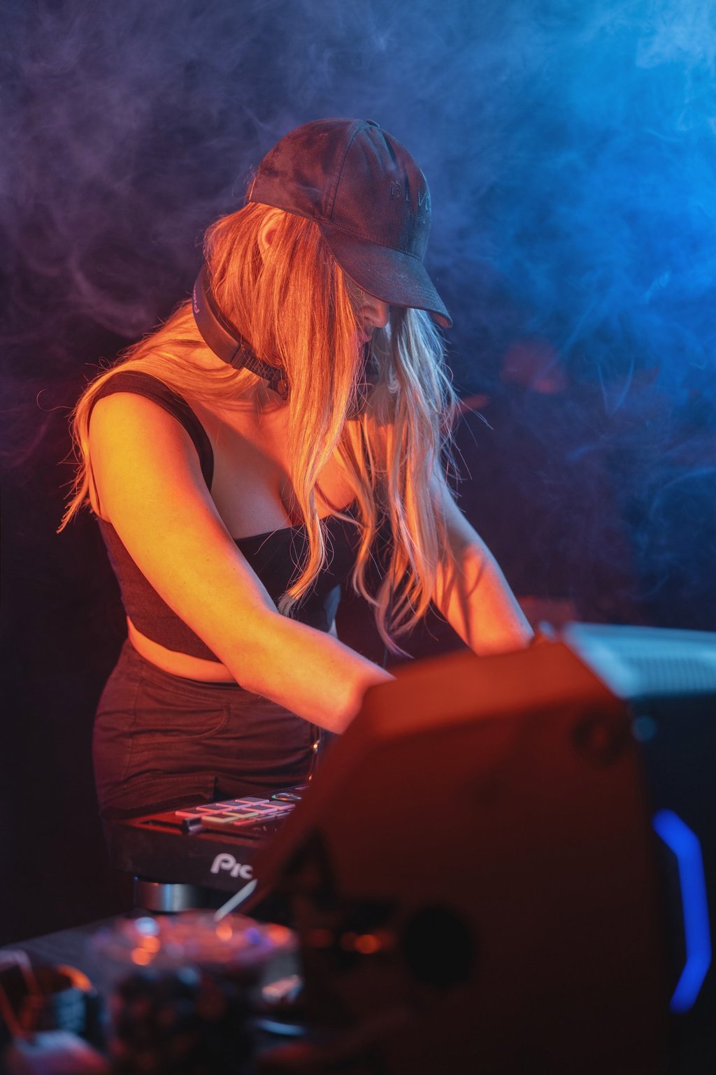 Kat Bendis wearing a black baseball cap mixing music on a DJ controller 