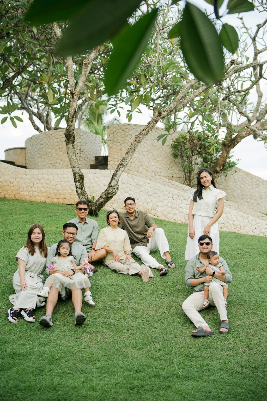 Large family enjoying time together in a tropical garden during a Bali family photography session.