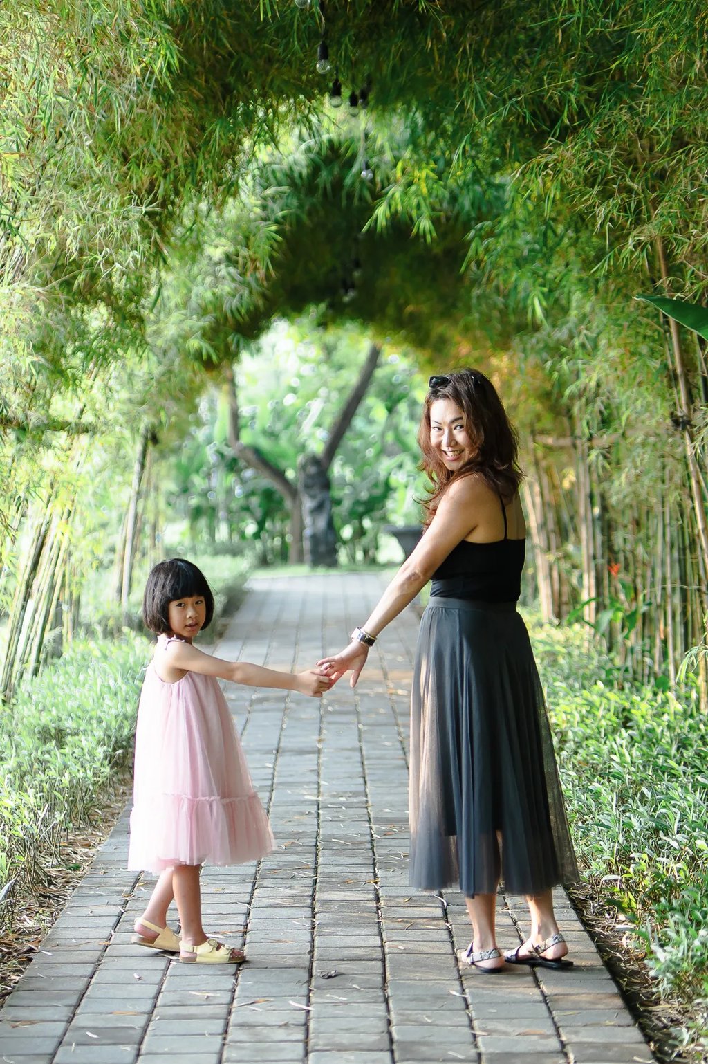 Mother and child walking together at Padma Resort Legian Bali surrounded by tropical garden atmosphere.