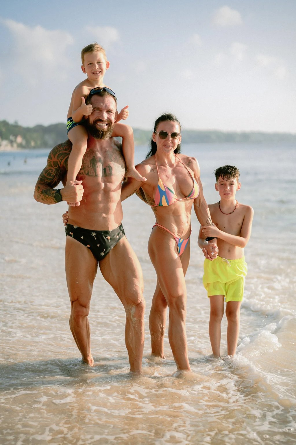 Family walking together through shallow ocean water during a sunset family photography session at Dreamland Beach Bali.