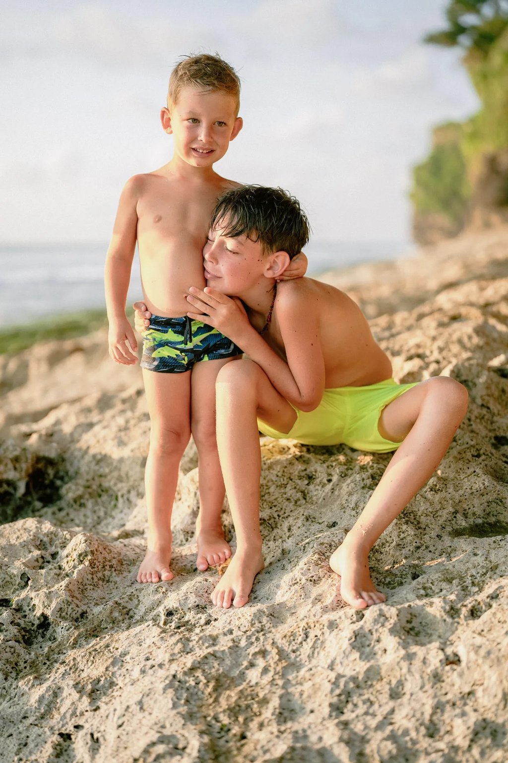 Mother sharing a quiet moment with her son on the cliffs of Dreamland Beach Bali during a family photo session.