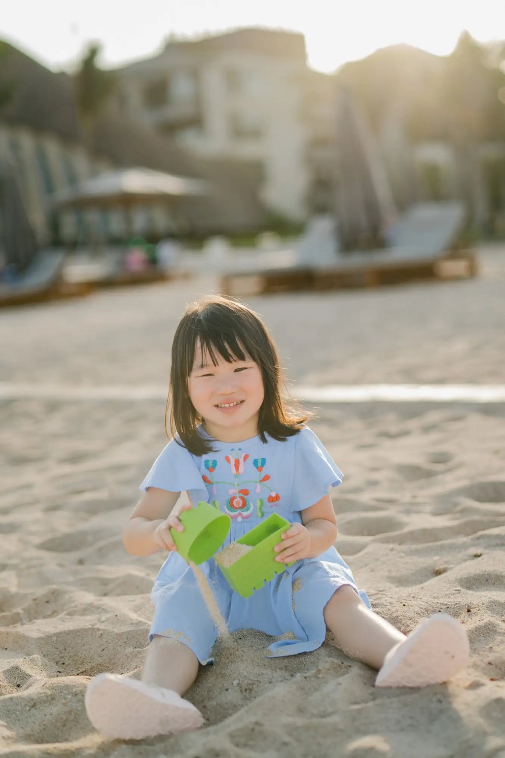 Young girl playing with sand during a family photography session at The Apurva Kempinski Bali.