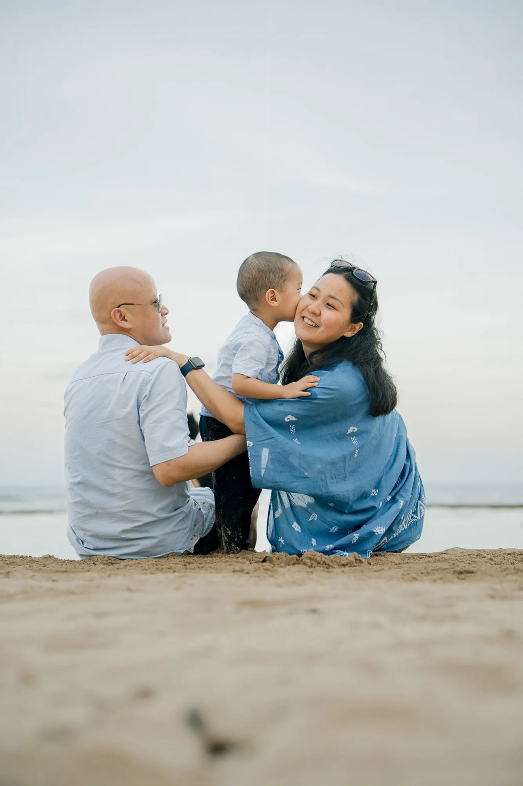 Parents and their son sharing a peaceful moment by the sea at Nusa Dua Beach Bali