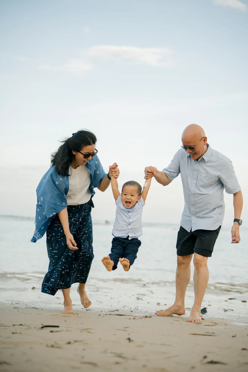 Parents lifting their son while enjoying a playful moment during a family photography session at Nusa Dua Beach Bali