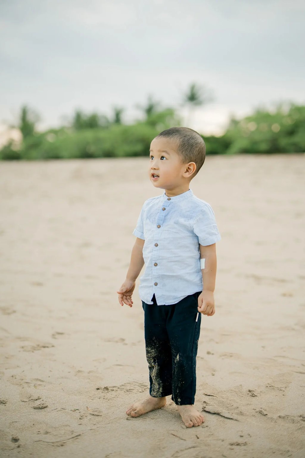 Young boy standing on the sand during a natural family photography session at Nusa Dua Beach Bali